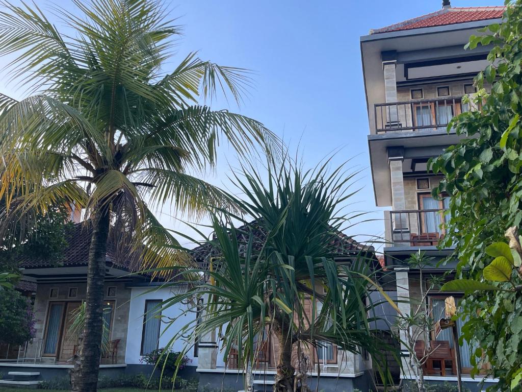 two palm trees in front of a building at Shipwreck Point Inn in Nusa Lembongan