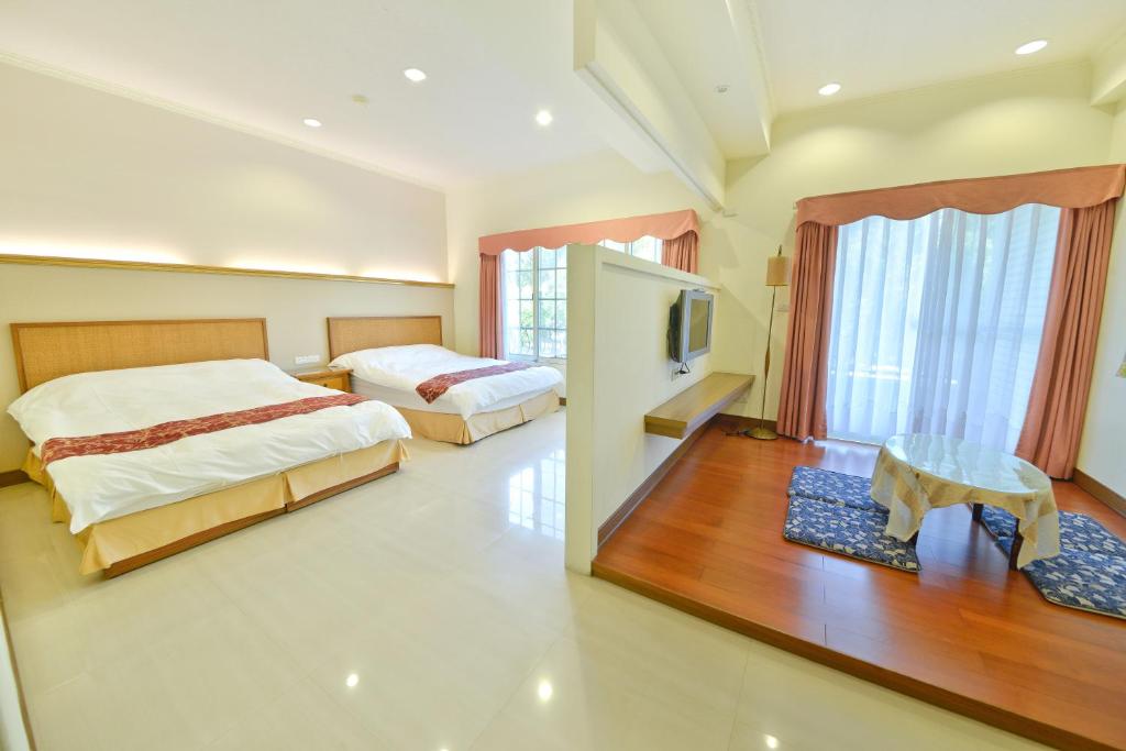 een grote slaapkamer met 2 bedden en een televisie bij Malia Homestay in Hualien
