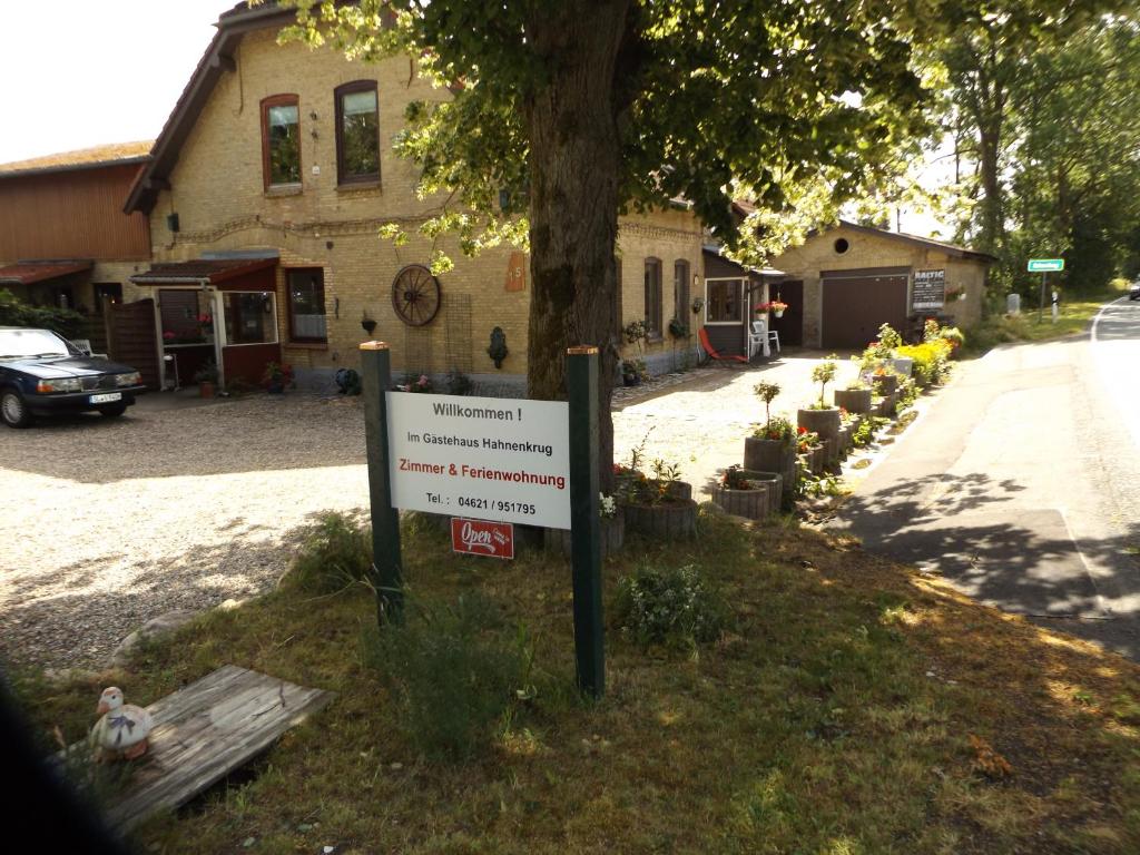 un cartel delante de un árbol delante de una casa en Ferienwohnung Hahnenkrug, en Selk