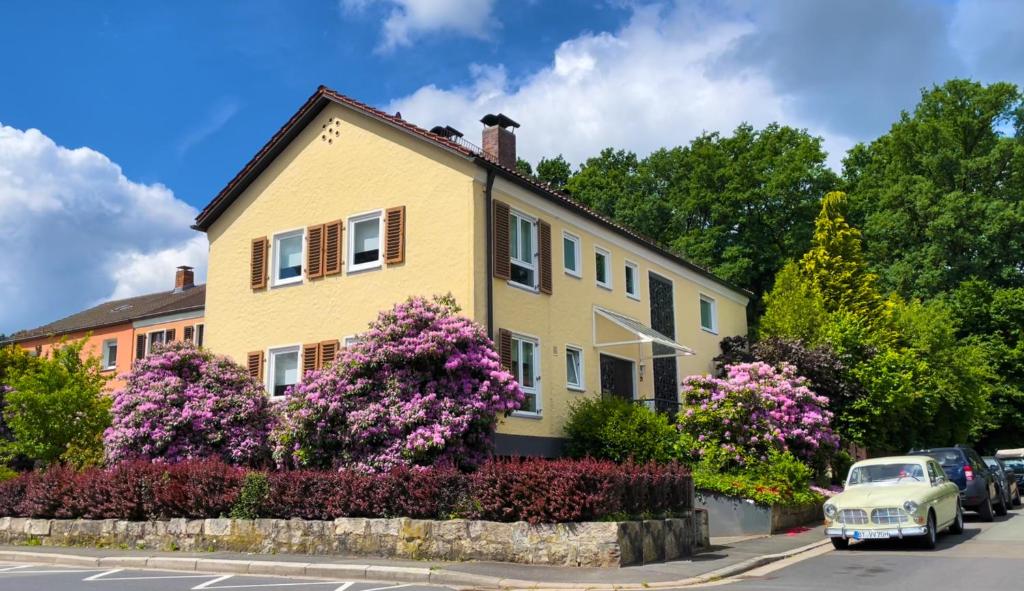 a yellow house with purple flowers on a street at HEJ Apartments Bayreuth in Bayreuth