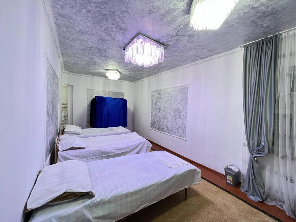 Habitación hospitalaria con 3 camas y ventana en Naryn Cozy House en Naryn