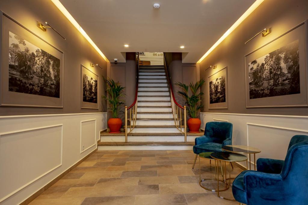 een lobby met blauwe stoelen en een trap bij Guest House Jacarandá Faro in Faro