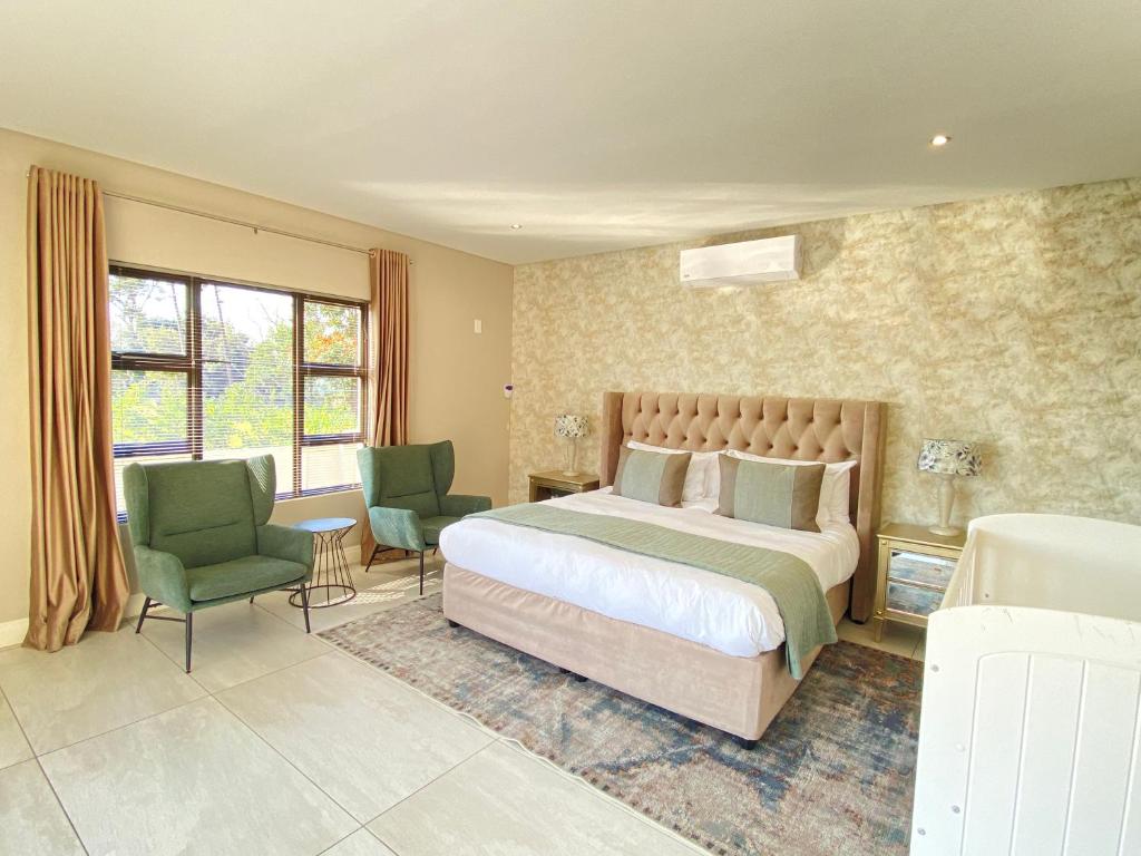a bedroom with a large bed and two chairs at Khaya Elihle Guest House in Hazyview