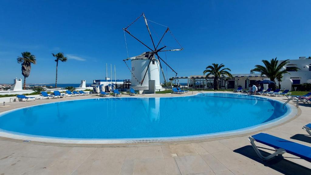 una gran piscina con un molino de viento en el fondo en All Dreams Apartment - Urbanização Windmill, en Albufeira