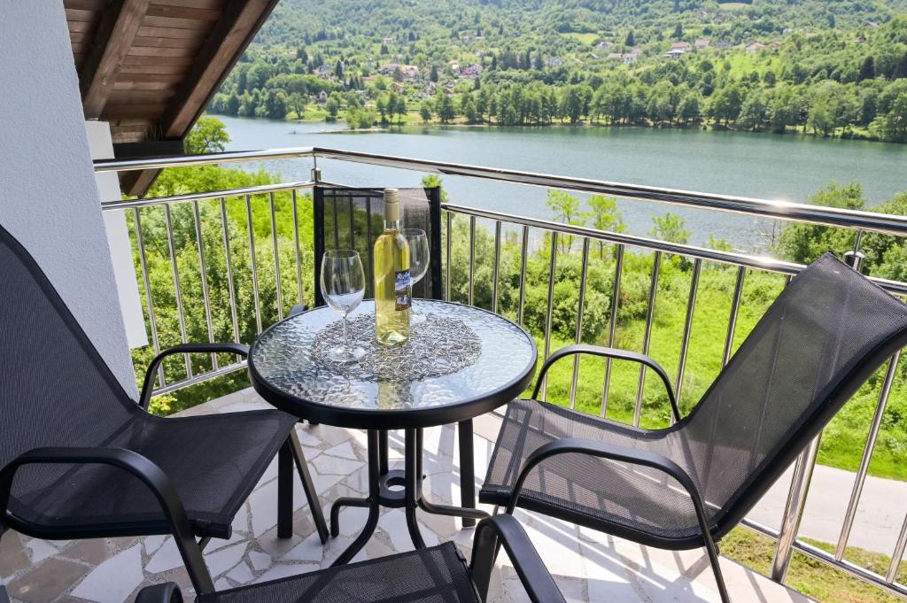 uma mesa com 2 copos de vinho e 2 cadeiras numa varanda em Villa Anita em Jajce
