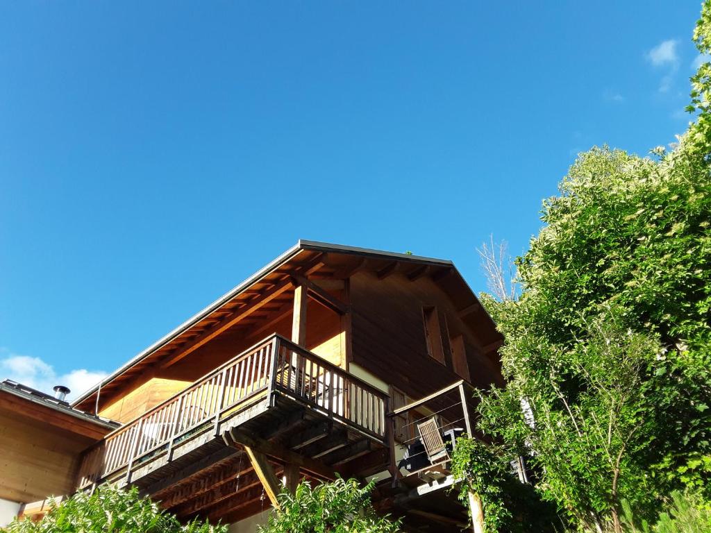 a log cabin with a balcony and trees at Comme à la maison à la montagne in Briançon