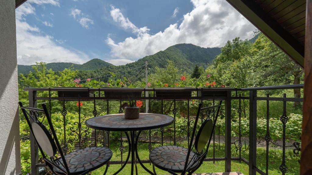 a table and chairs on a balcony with mountains in the background at Holiday house Kajfes in Brod na Kupi