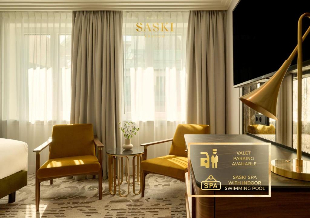 een hotelkamer met 2 stoelen en een bord met hulp bij Hotel Saski Krakow Curio Collection by Hilton in Krakau