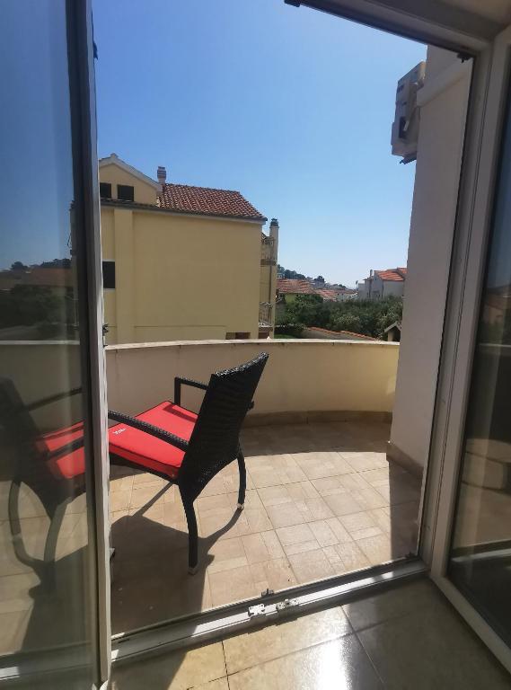 a balcony with a red chair and a window at Apartmani Lešić Tribunj in Tribunj