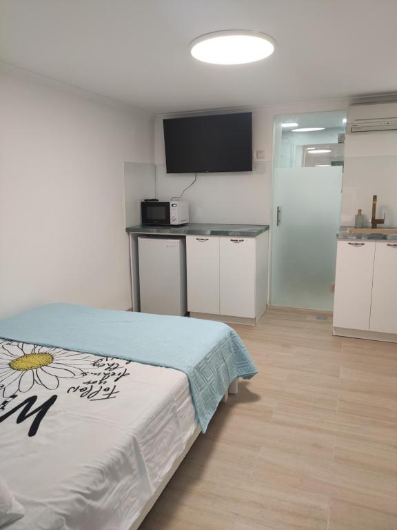 a bedroom with a bed and a kitchen with a counter at Emilie Guest House in Haifa