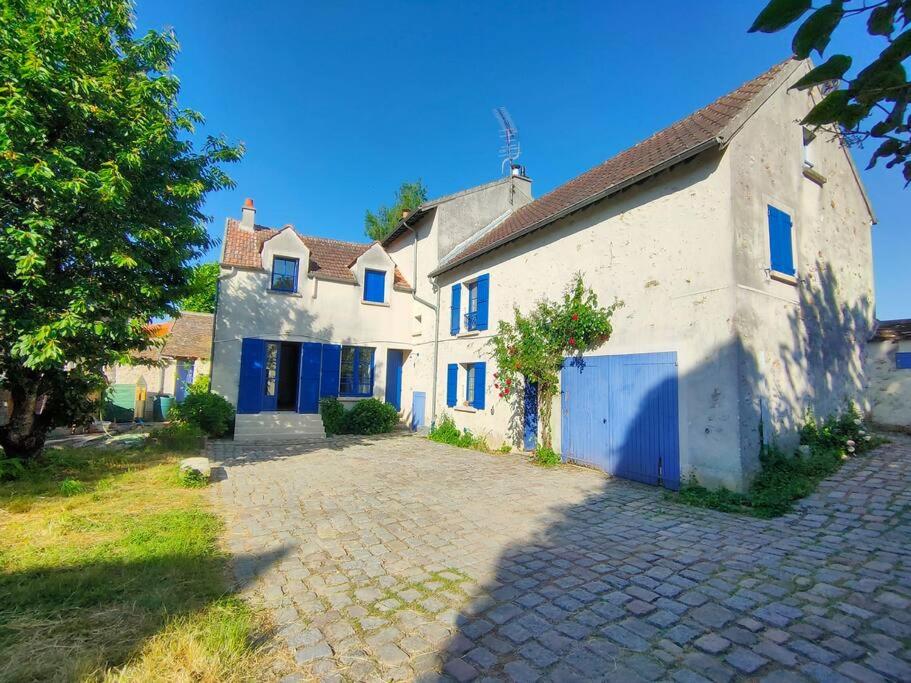 a large white house with blue windows and a driveway at Ancienne ferme Chessy in Chessy