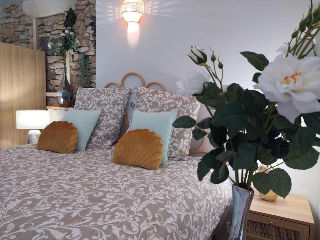 um quarto com uma cama com almofadas e um vaso de flores em La perle de Gordes em Gordes
