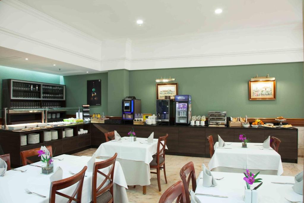 a restaurant with white tables and chairs and a counter at Hotel Principe Paz in Santa Cruz de Tenerife