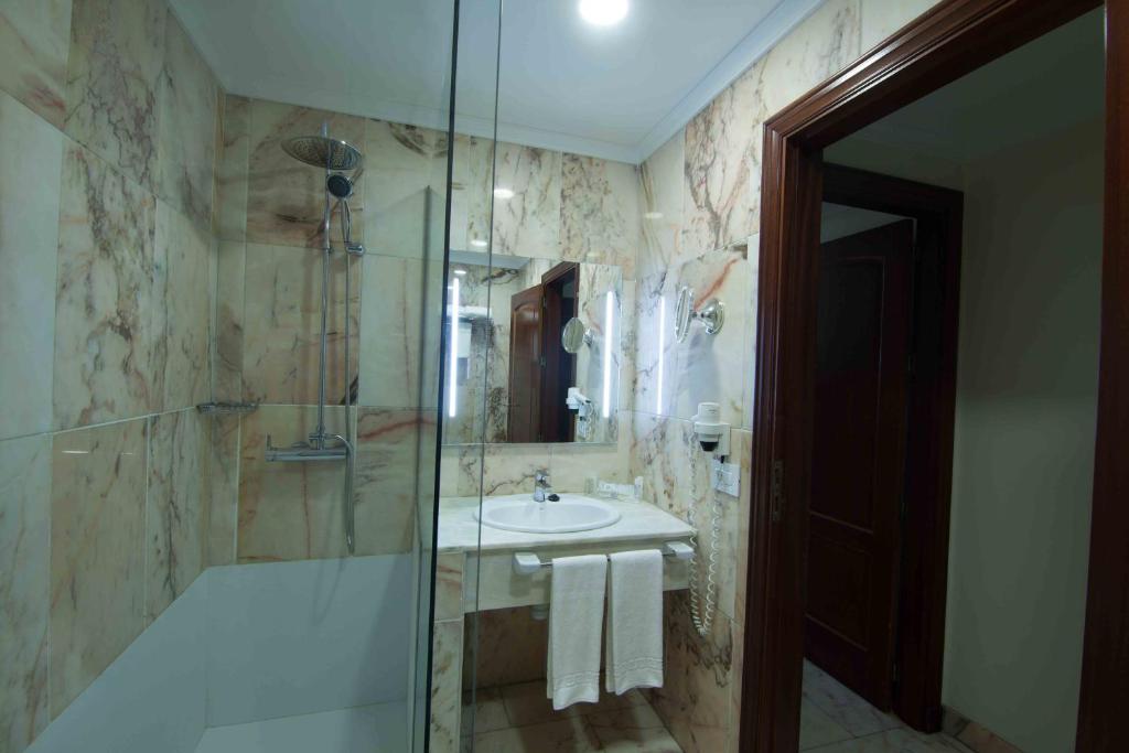 a bathroom with a sink and a glass shower at Hotel Principe Paz in Santa Cruz de Tenerife