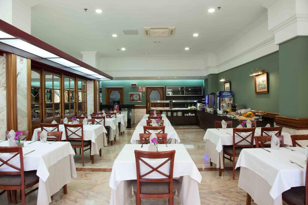 a restaurant with white tables and chairs and a counter at Hotel Principe Paz in Santa Cruz de Tenerife
