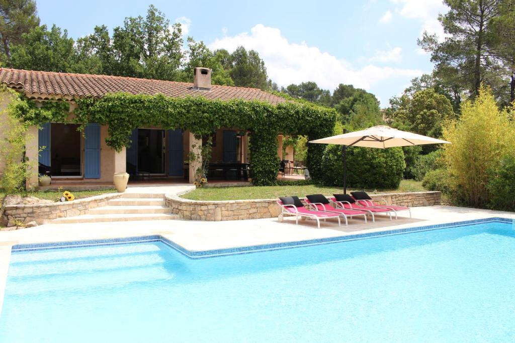 une piscine avec des chaises et un parasol à côté d'une maison dans l'établissement Villa en Provence, à Flayosc
