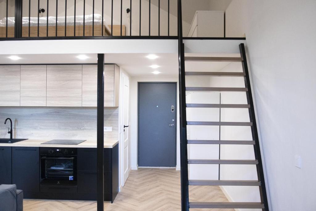 a loft bed with a kitchen in a room at Sniego Apartments in Vilnius
