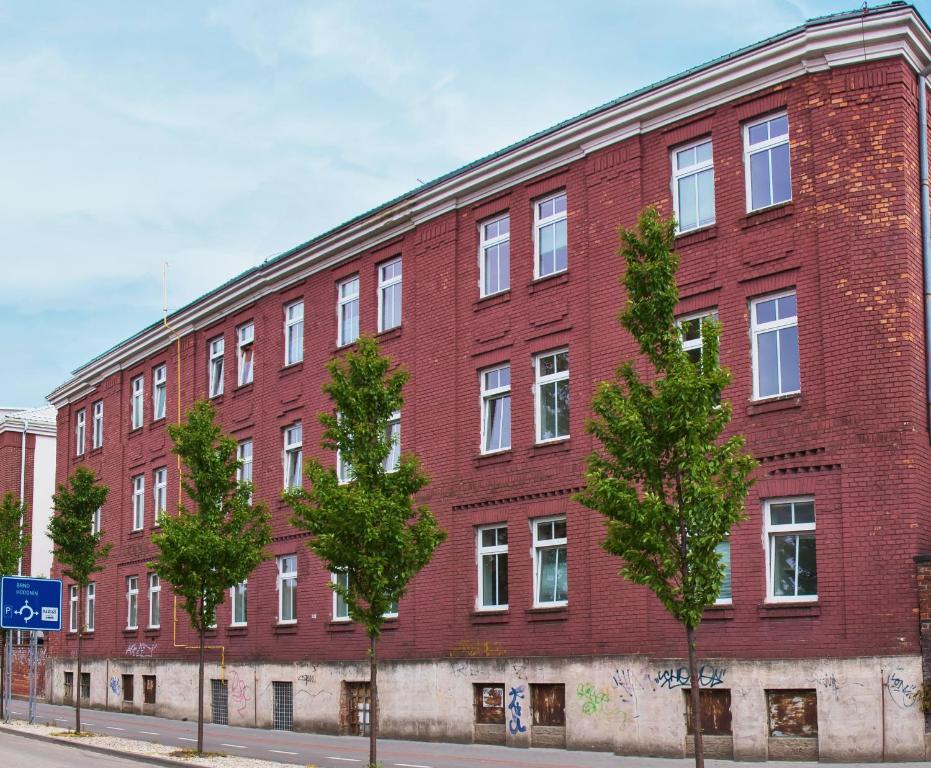 a red brick building with trees in front of it at Centrum Ubytování Břeclav in Břeclav