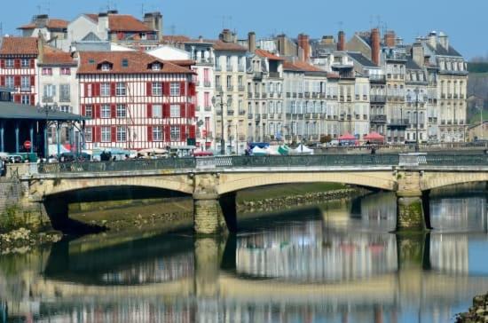 a bridge over a river in a city with buildings at Le Chalet d&#39;Amou in Bayonne
