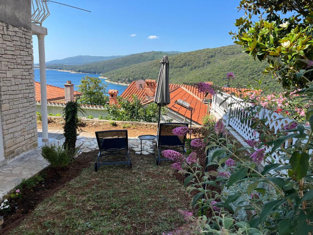 a patio with two chairs and an umbrella at Apartments Zahtila - Pina in Rabac