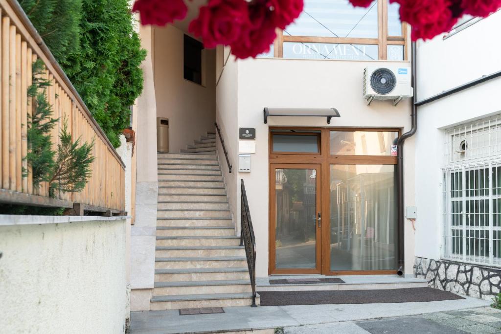 eine Treppe, die zu einer Tür mit roten Blumen führt in der Unterkunft Ornament Hotel and Apartments in Sarajevo