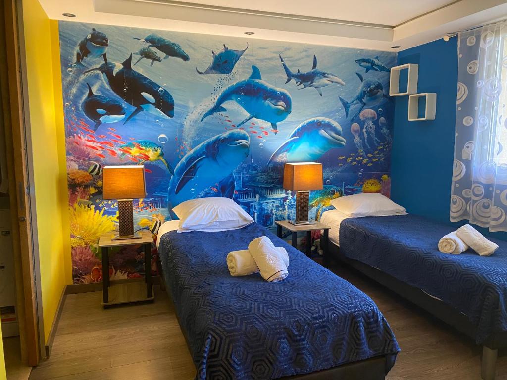 Habitación con 2 camas y un mural de delfines. en Résidence Les Eucalyptus, en Antibes