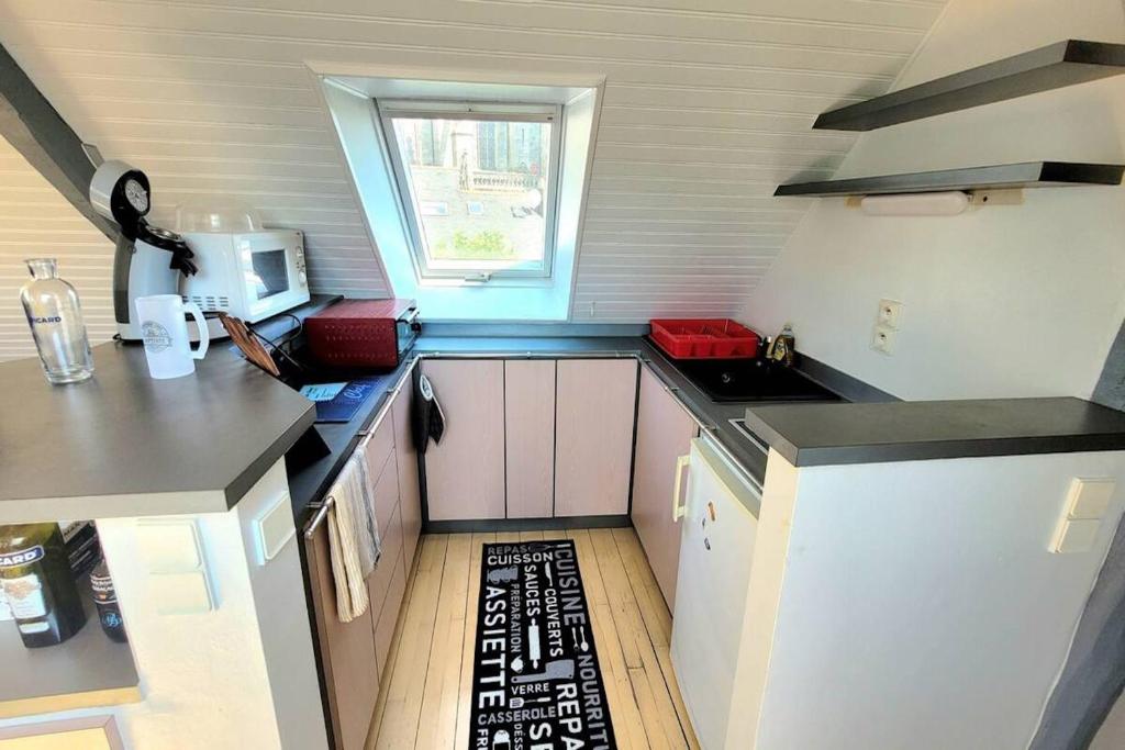 a small kitchen with white cabinets and a window at Studio Design Sous Toits IntraMuros Vue Cathédrale in Vannes
