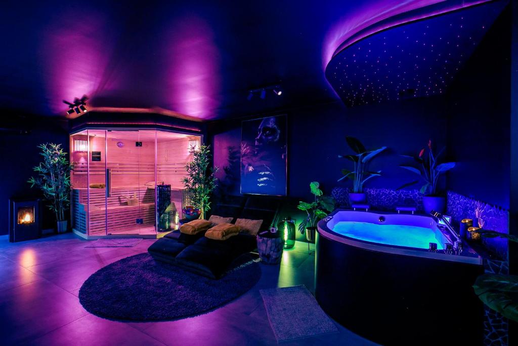 a purple room with a tub and a room with a couch at Merkelhoeve Wellness in Merkelbeek