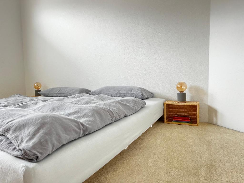 a white bed with gray sheets and a night stand at Rosenfeld 2 in Pinneberg