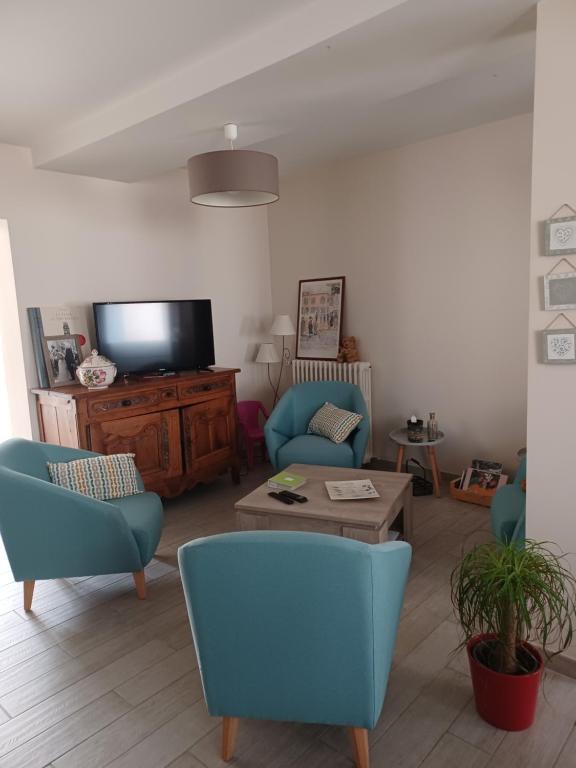a living room with two blue chairs and a tv at Entre Loire et canal in Briare