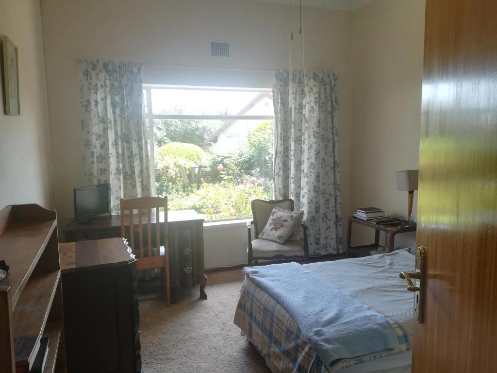 a bedroom with a bed and a desk and a window at BEDFORDVIEW BandB in Bedfordview