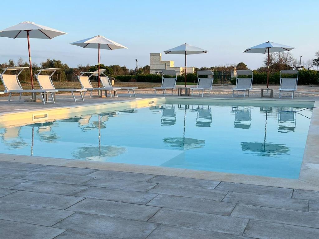 a swimming pool with chairs and umbrellas at Tenuta Corano Nardò in Nardò