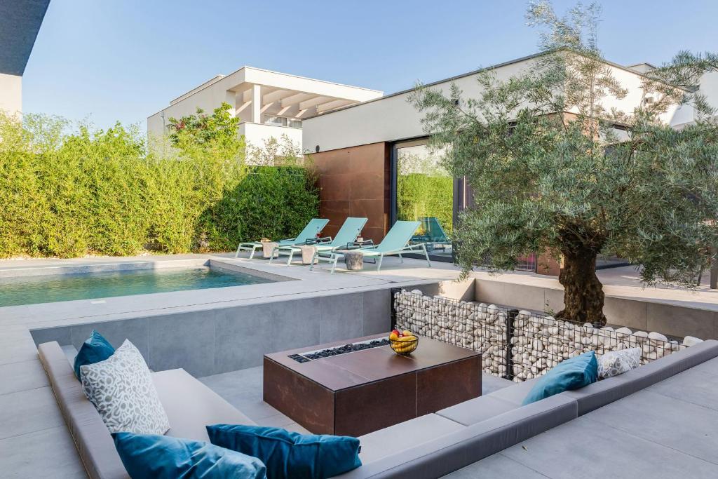 een patio met een bank en een tafel naast een zwembad bij Villa Marli ZadarVillas in Zaton