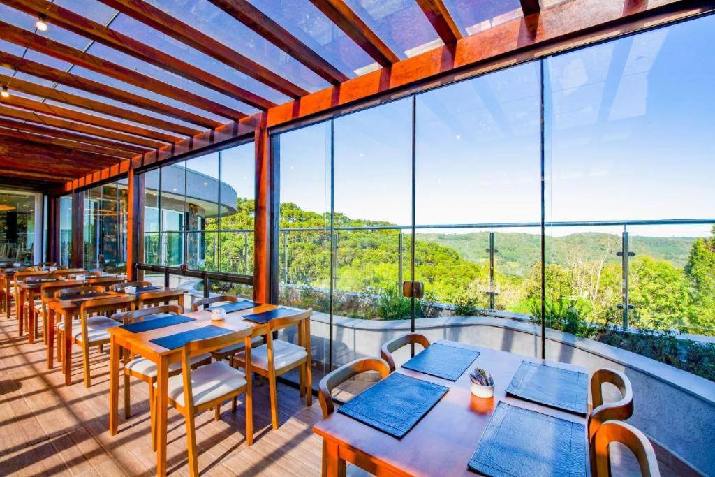 restauracja ze stołami i krzesłami oraz dużym oknem w obiekcie Laghetto Resort Golden Oficial - Particular w mieście Gramado