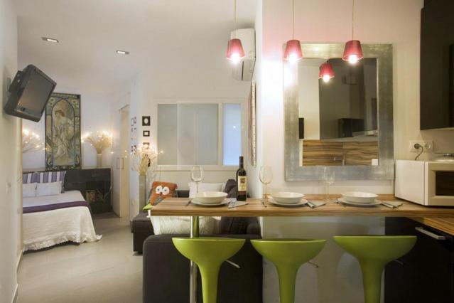 a living room with a kitchen with green stools at City Center Apartment in Barcelona