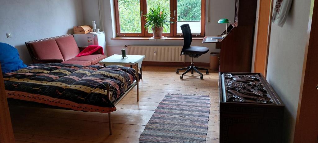 a living room with a bed and a desk and a chair at Helles großes Zimmer mit eigenem Bad in Kassel