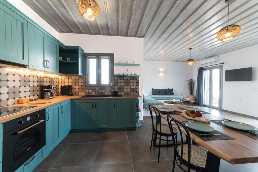 a kitchen with blue cabinets and a table with chairs at Falakis Apartments in Kithnos