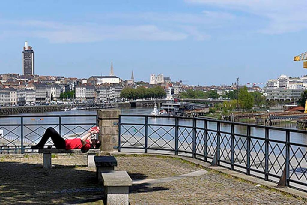 a person laying on a bench next to a body of water at Un jardin en ville in Nantes