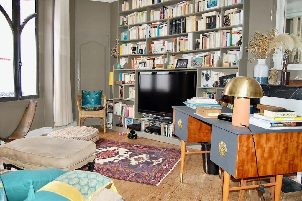a living room with a large book shelf filled with books at Un jardin en ville in Nantes