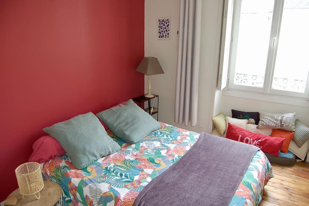 a bedroom with a bed and a red wall at Un jardin en ville in Nantes