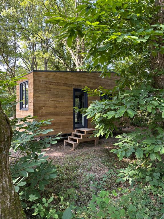 une petite cabane en bois avec un banc dans les bois dans l'établissement Tiny house, à Saint-Lyphard