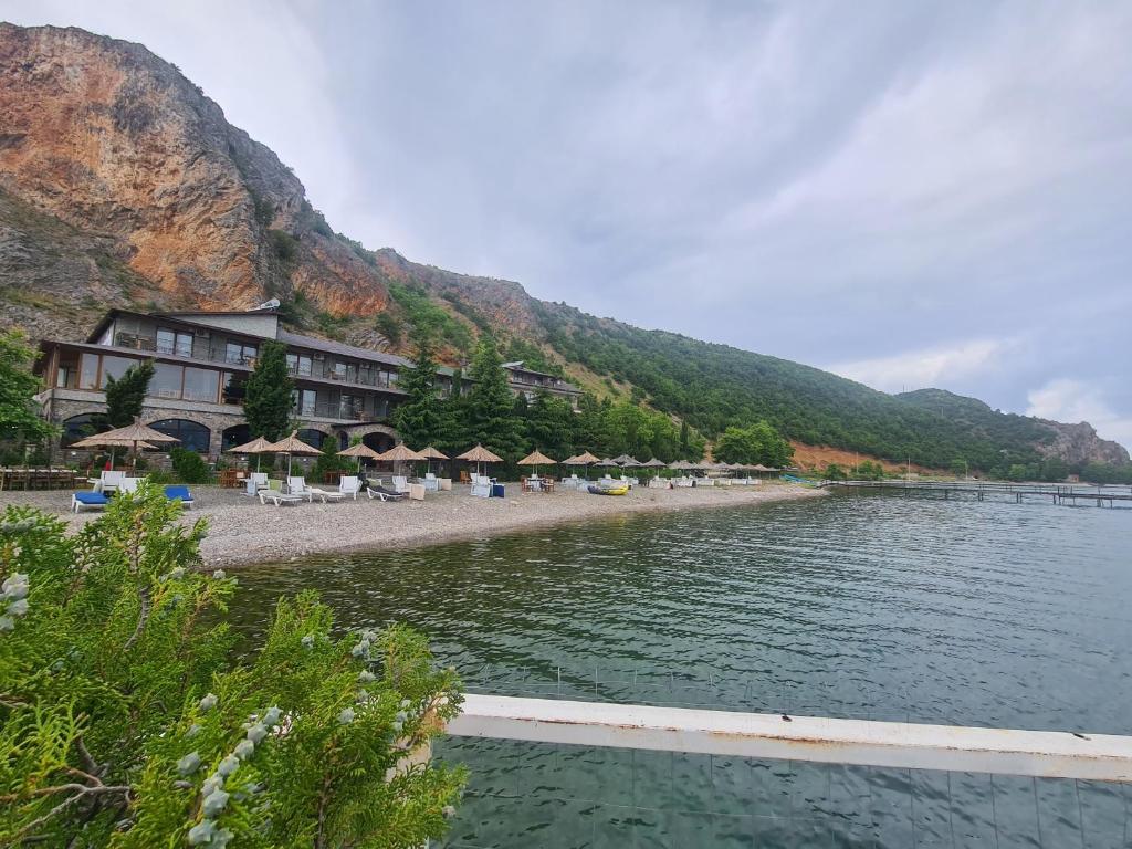 a beach with chairs and umbrellas and a hotel at Hotel Kukesi in Pogradec