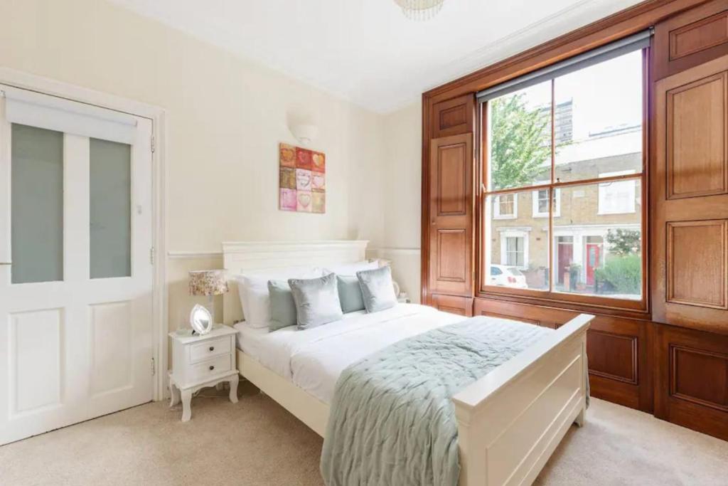 a bedroom with a large white bed and a window at Charming 3BD Flat - 5 Minutes to Victoria Park in London