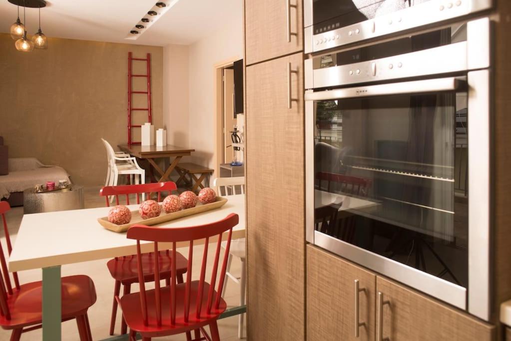 een keuken met een tafel met rode stoelen en een oven bij Deluxe apartment in the center in Kalamata