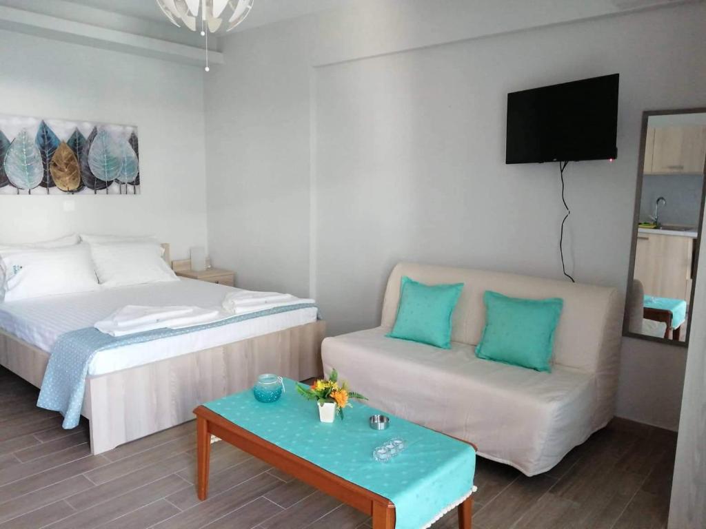 een kamer met 2 bedden, een bank en een tv bij PERLA apartments in Paralia Dionysiou