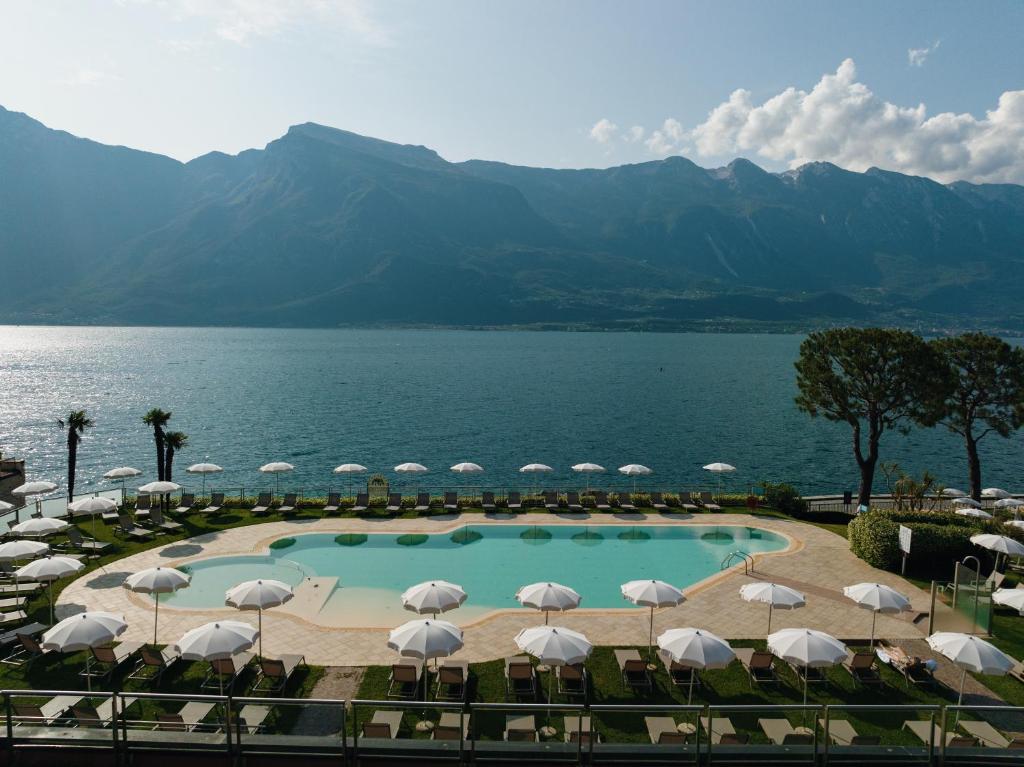 a view of a pool with umbrellas and the water at Hotel Du Lac in Limone sul Garda