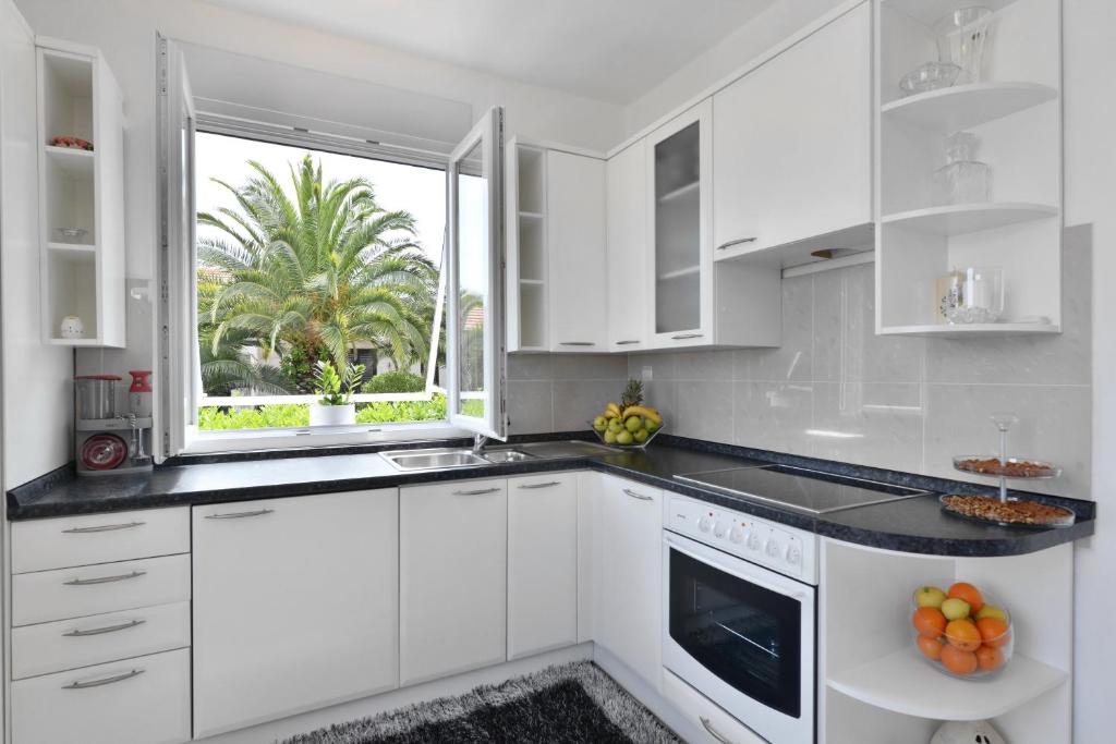 a white kitchen with a sink and a window at Villa Sarah in Supetar
