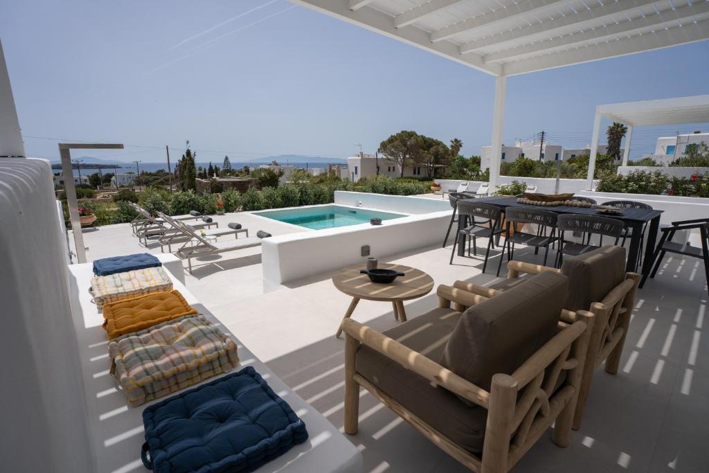 a patio with a pool and chairs and a table at Paros Breeze Luxury Villa in Drios