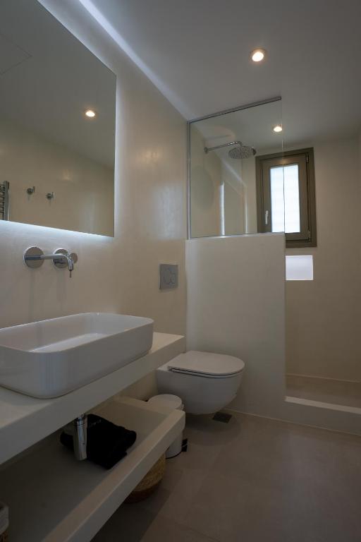 a bathroom with a sink and a toilet and a mirror at Paros Breeze Luxury Villa in Drios
