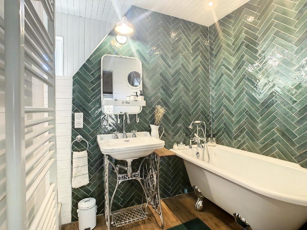 La salle de bains est pourvue d'un lavabo et d'une baignoire à côté de la baignoire. dans l'établissement Le Grenier du Buronnier, à Saint-Simon